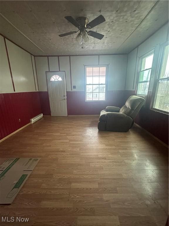 unfurnished room with wood-type flooring, ceiling fan, and a baseboard radiator