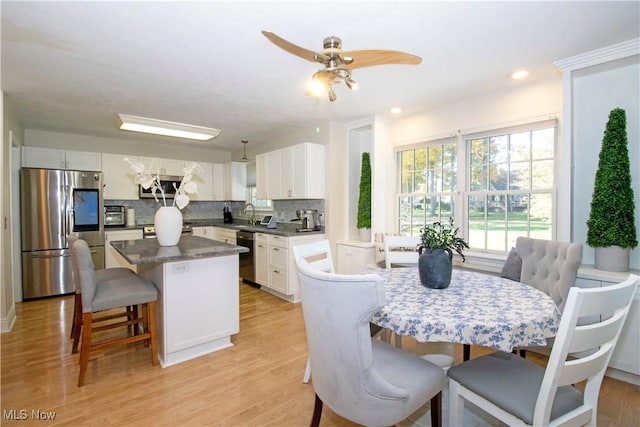 dining space featuring sink, ceiling fan, and light wood-type flooring