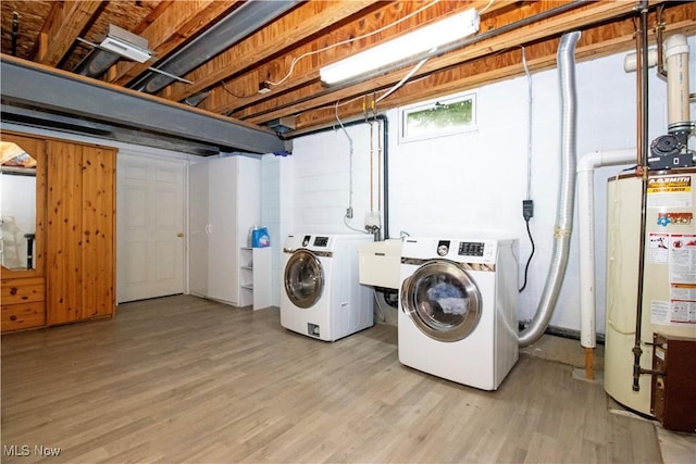 washroom with sink, light wood-type flooring, water heater, and washing machine and clothes dryer