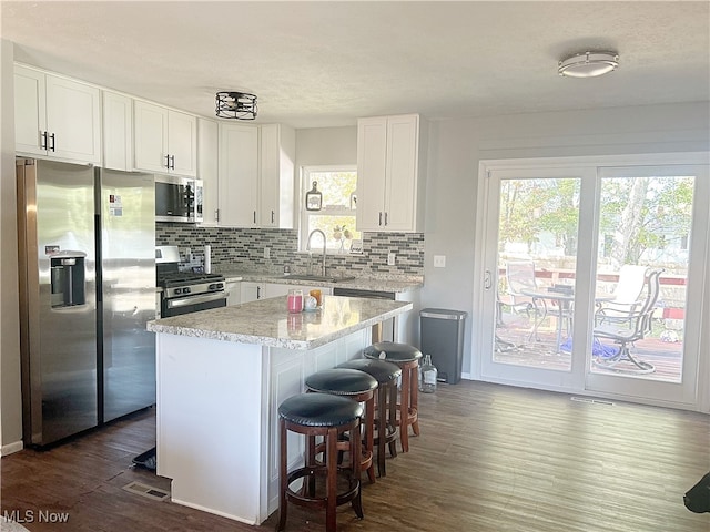 kitchen featuring a kitchen island, dark hardwood / wood-style floors, sink, white cabinets, and appliances with stainless steel finishes