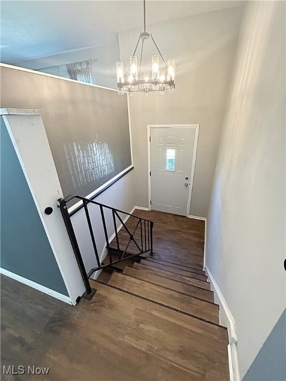 stairs with hardwood / wood-style floors and a notable chandelier