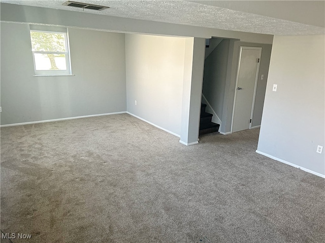 basement featuring light carpet and a textured ceiling