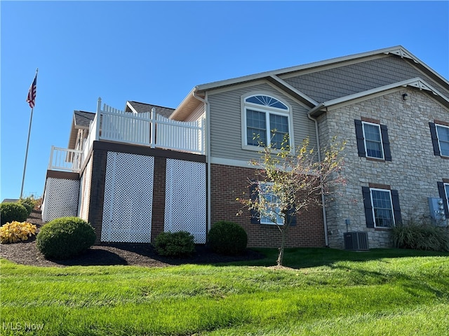 view of front of home with a front yard, central air condition unit, and a wooden deck