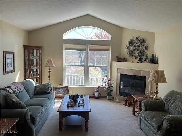 carpeted living room with a textured ceiling, a tile fireplace, and vaulted ceiling