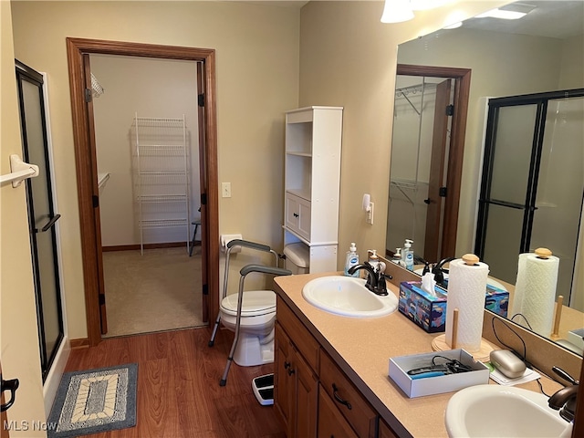 bathroom with vanity, toilet, wood-type flooring, and a shower with shower door