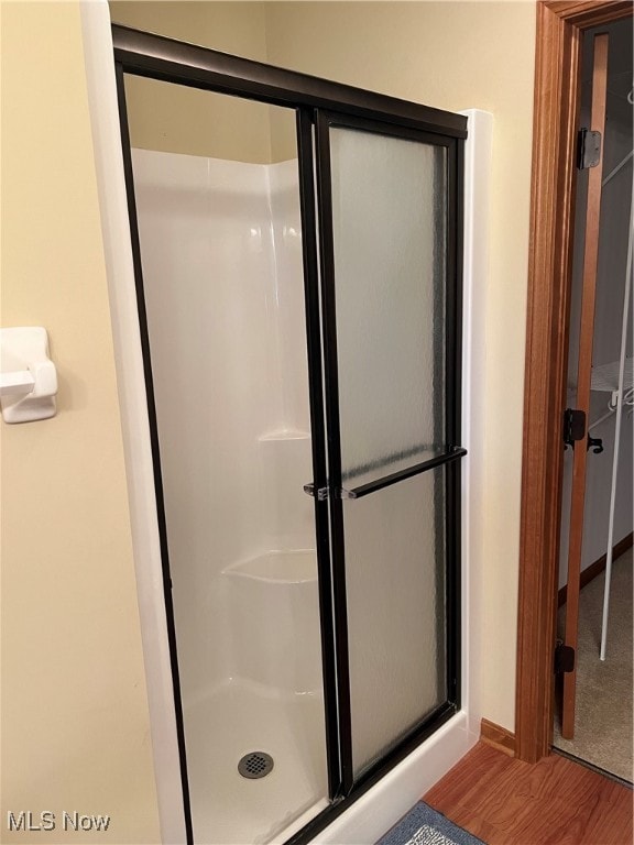 bathroom featuring a shower with door and wood-type flooring