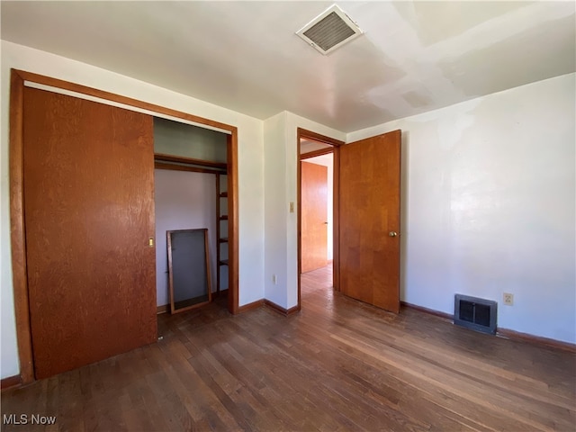 unfurnished bedroom with a closet and dark hardwood / wood-style flooring