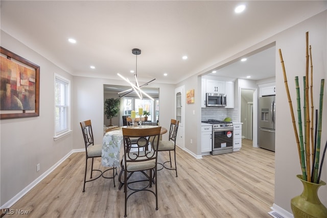 dining space with light hardwood / wood-style floors and a notable chandelier