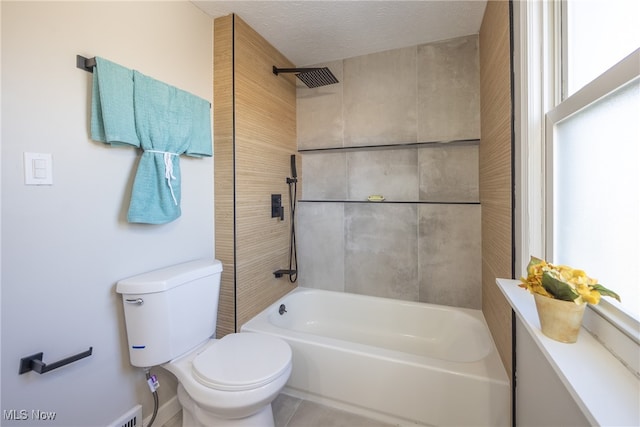 bathroom featuring tiled shower / bath combo, a textured ceiling, and toilet