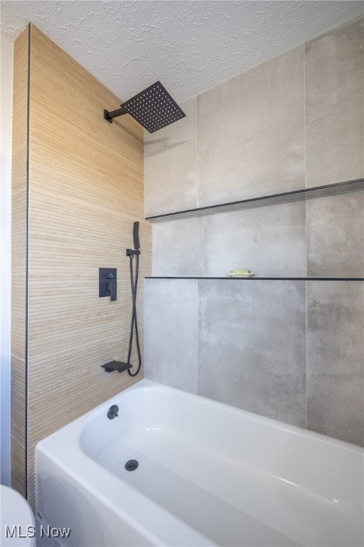 bathroom featuring tiled shower / bath combo, a textured ceiling, and toilet