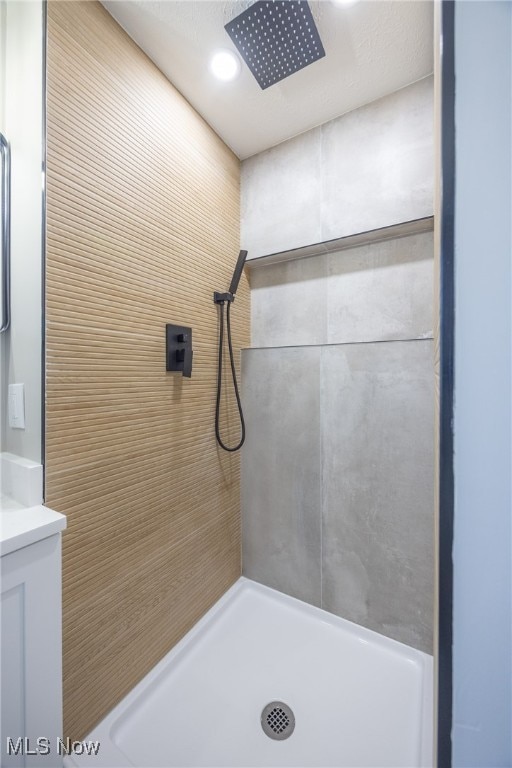 bathroom featuring a tile shower and vanity