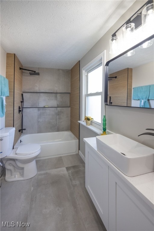 full bathroom with vanity, toilet, a textured ceiling, and tiled shower / bath