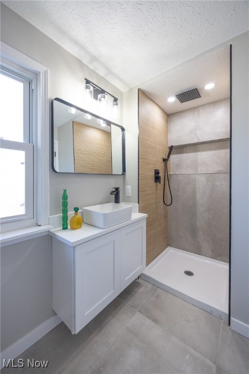 bathroom featuring a wealth of natural light, tiled shower, and vanity