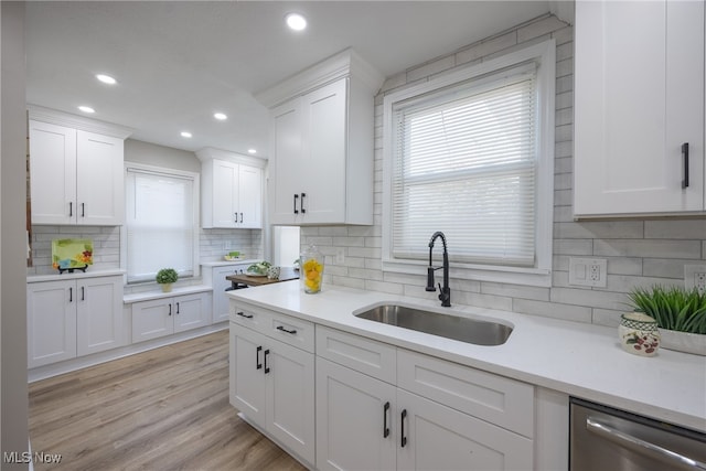 kitchen featuring dishwasher, sink, light wood-type flooring, and white cabinets