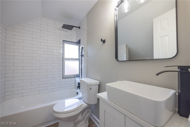 full bathroom with tiled shower / bath, vanity, lofted ceiling, and toilet