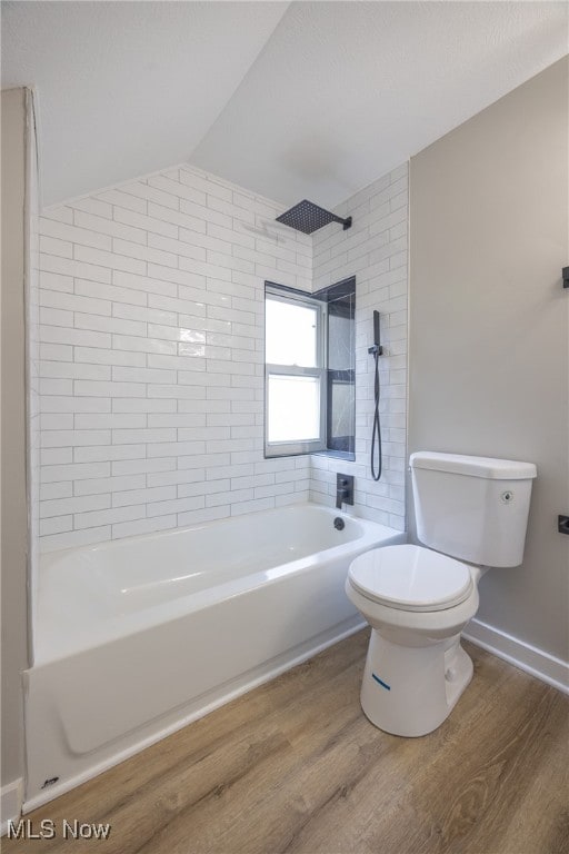 bathroom with toilet, hardwood / wood-style flooring, vaulted ceiling, and tiled shower / bath