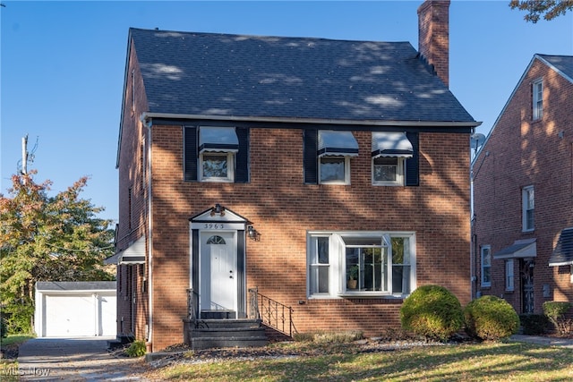 colonial-style house featuring a front yard, an outbuilding, and a garage