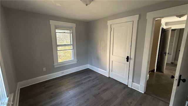 unfurnished bedroom with dark wood-type flooring and a closet