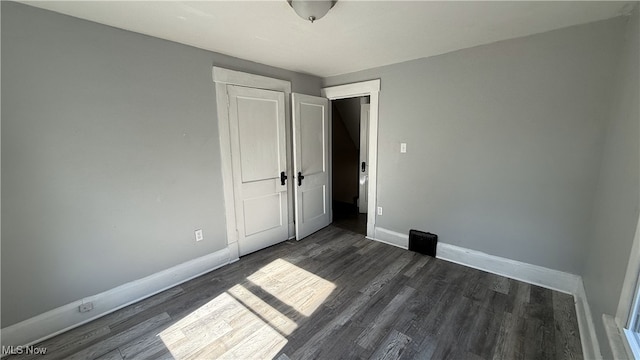 unfurnished bedroom with dark hardwood / wood-style flooring