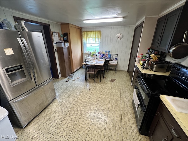 kitchen featuring stainless steel fridge, black electric range, and wooden walls