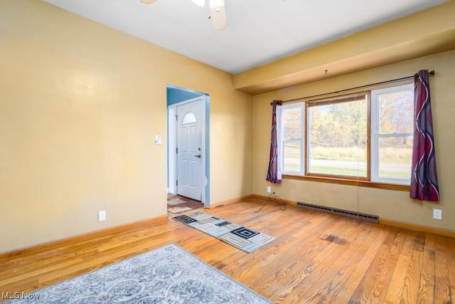 empty room featuring a baseboard heating unit, light hardwood / wood-style floors, and ceiling fan