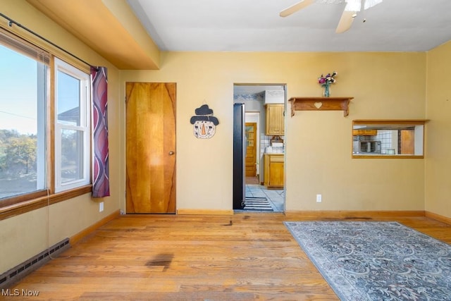 empty room featuring a baseboard radiator, light hardwood / wood-style flooring, and ceiling fan