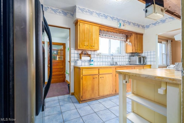 kitchen with backsplash, stainless steel refrigerator, and light tile patterned floors