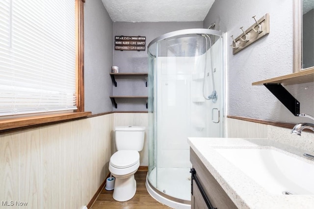 bathroom with a shower with door, a textured ceiling, toilet, vanity, and hardwood / wood-style flooring