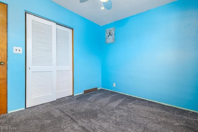 unfurnished bedroom with a closet, ceiling fan, and dark carpet