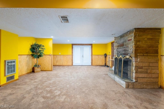 unfurnished living room with a textured ceiling, carpet flooring, heating unit, and a fireplace