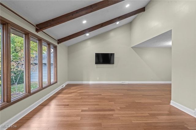 spare room with light hardwood / wood-style flooring and vaulted ceiling with beams