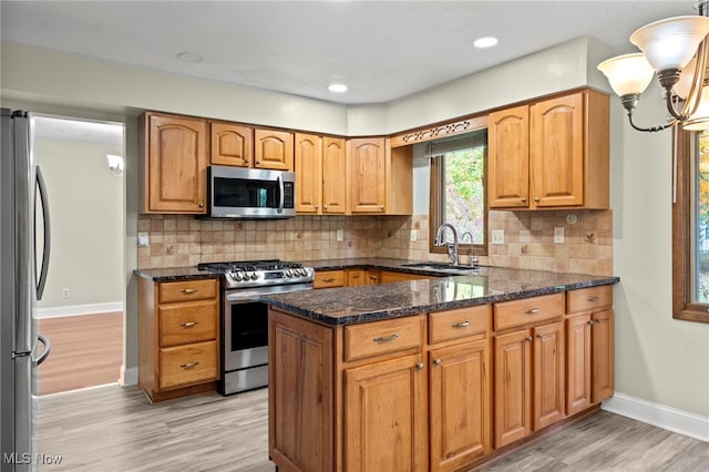 kitchen with appliances with stainless steel finishes, decorative backsplash, sink, and light hardwood / wood-style floors