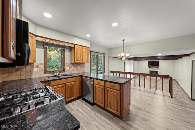 kitchen with appliances with stainless steel finishes, sink, light hardwood / wood-style floors, decorative light fixtures, and a chandelier