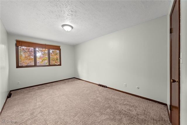 carpeted empty room featuring a textured ceiling