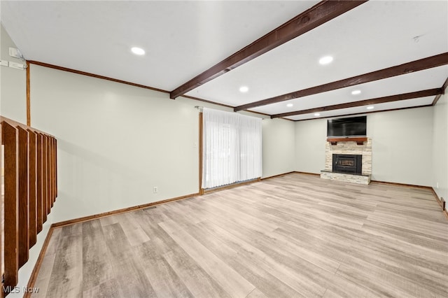 unfurnished living room featuring a fireplace, beamed ceiling, and light wood-type flooring