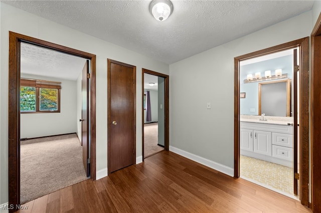 unfurnished bedroom with ensuite bathroom, wood-type flooring, and a textured ceiling