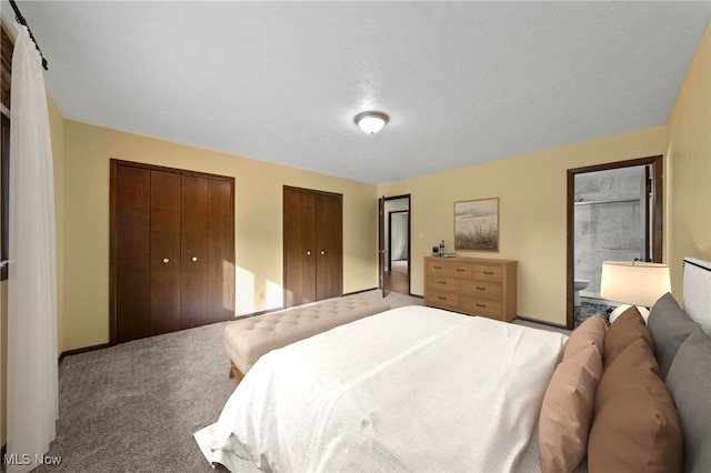 bedroom with carpet floors, two closets, a textured ceiling, and connected bathroom