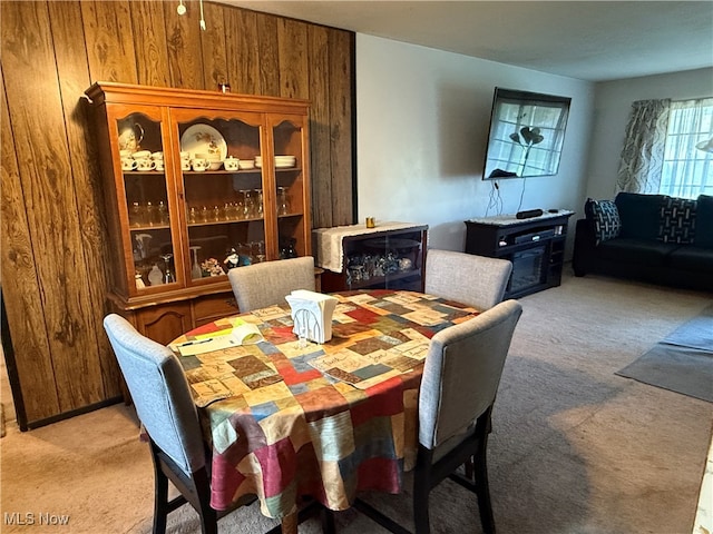 carpeted dining area with wood walls