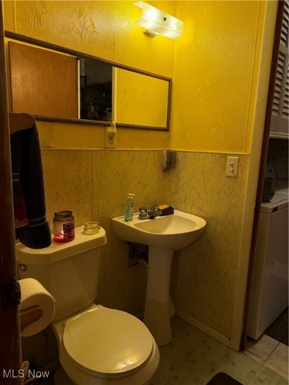 bathroom featuring washer / dryer, sink, and toilet