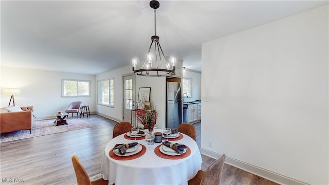 dining space featuring sink, hardwood / wood-style flooring, and an inviting chandelier