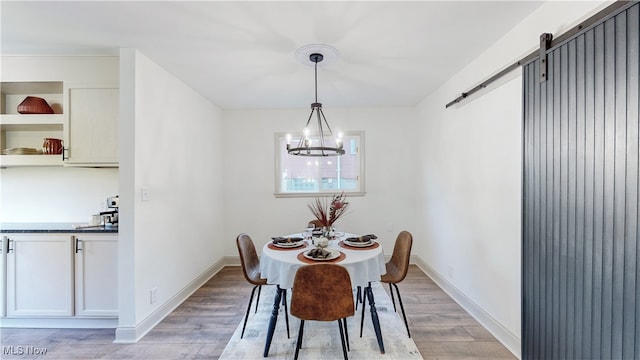 dining space featuring an inviting chandelier, light wood-type flooring, and a barn door