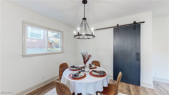 dining room with hardwood / wood-style flooring, an inviting chandelier, and a barn door