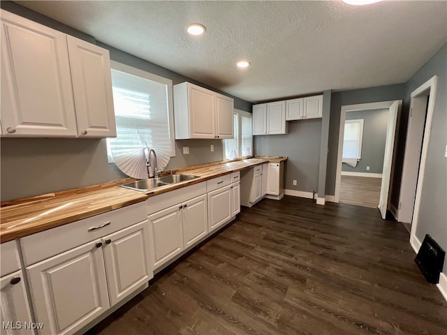 kitchen featuring a textured ceiling, white cabinetry, dark hardwood / wood-style floors, wooden counters, and sink