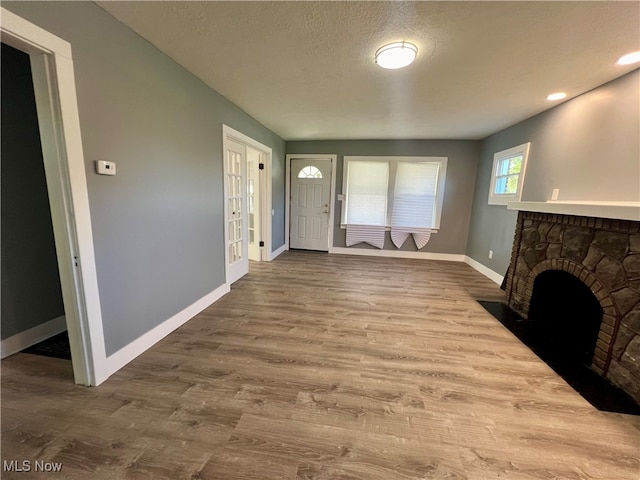 foyer with hardwood / wood-style flooring, a textured ceiling, and a fireplace