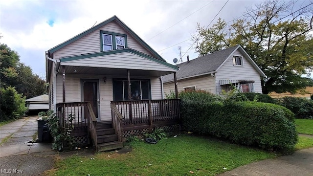 bungalow-style house with covered porch, a front yard, and a garage