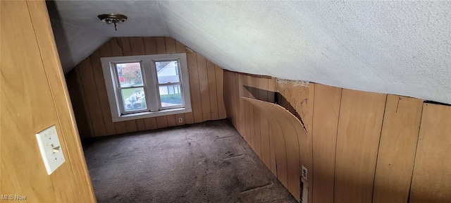 bonus room featuring wood walls, a textured ceiling, carpet flooring, and vaulted ceiling