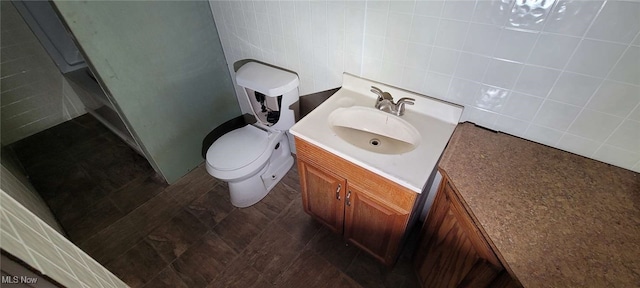 bathroom with vanity, toilet, and tile walls