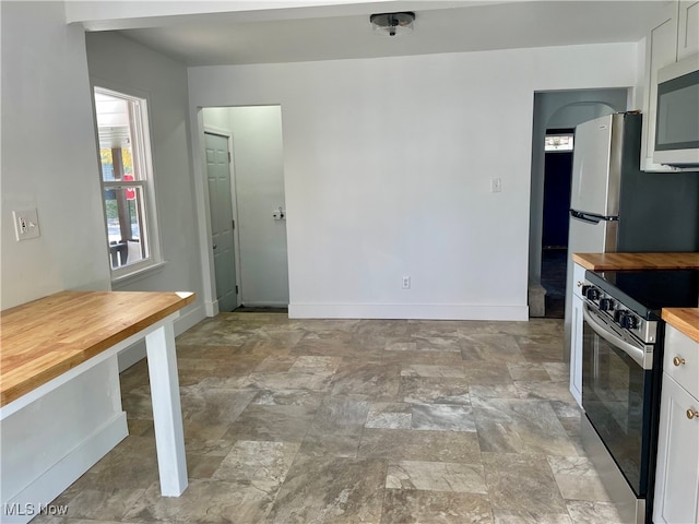 kitchen with white cabinetry, stainless steel appliances, and wood counters