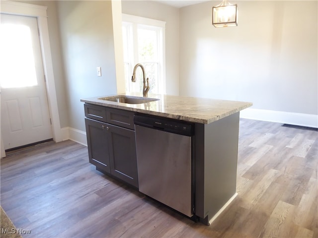 kitchen with sink, dishwasher, an island with sink, decorative light fixtures, and light hardwood / wood-style flooring