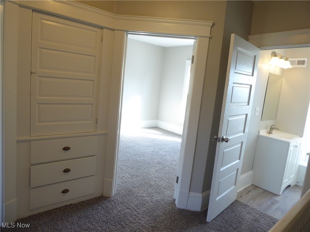 corridor featuring sink and light colored carpet